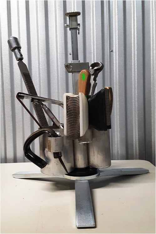 Photo of Jaime Jackson's professional tripod hoof stand with tool caddy, the most sophisticated tripod hoof stand especially designed for the natural hoof care practitioners designed by a former farrier and hoof care expert. It includes height adjustment and flip cradle. On display are RR-1, RR-2, Sole rasp, GE Forge nippers, hoof pick, hoof buffer.